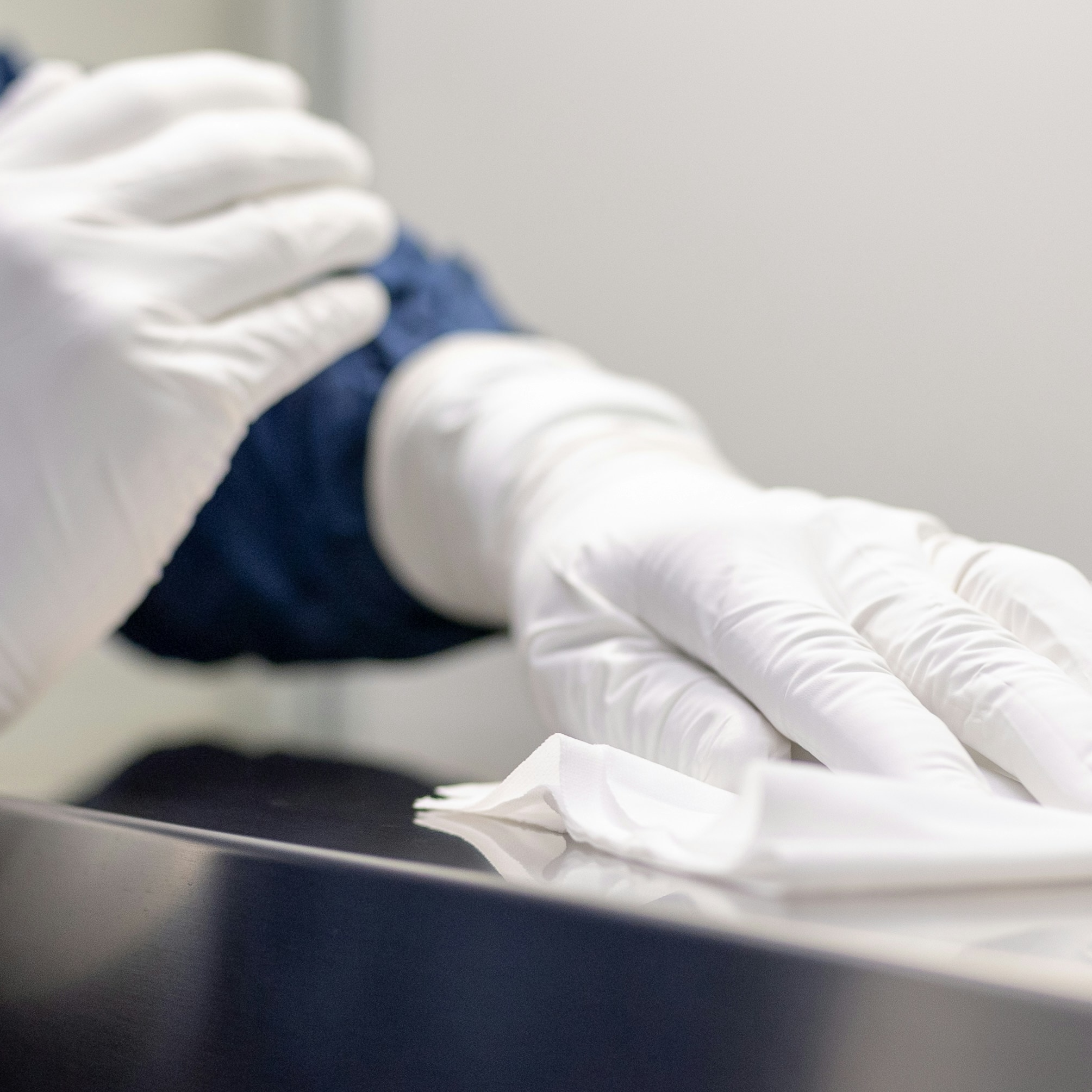 Hands with white gloves cleaning a metal surface